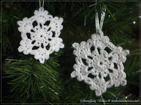 two crochet snowflakes hanging in a christmas tree - www.wishesintherain.net