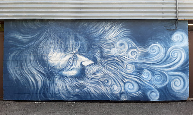 Long mural in blues and whites, of a long haired old man with beard and moustache, breathing out swirls