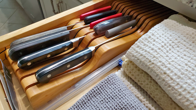 Knives stored in a kitchen drawer in a bamboo block.