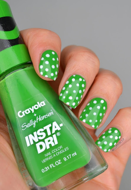 green polka dot nail art holding green nail polish bottle