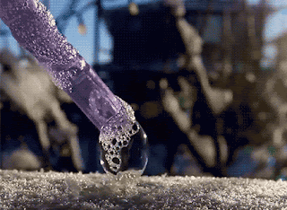 A purple tube blowing a bubble that quickly turns to frost.
