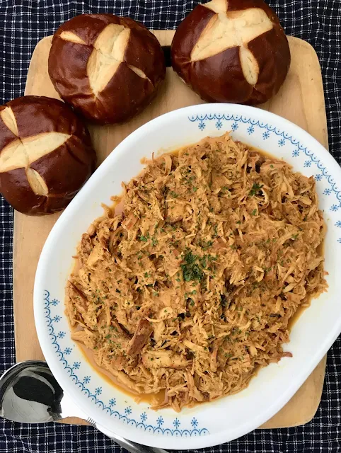 Platter filled with shredded honey mustard chicken and pretzel rolls..