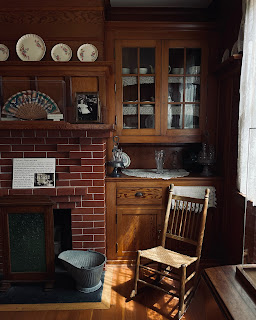 A rocking chair, and bookshelf by a fireplace