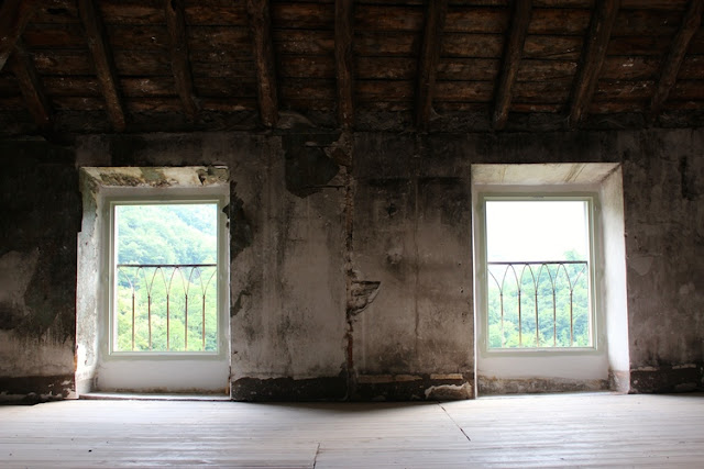 Decaying interior room of French Chateau Gudanes with windows overlooking mountains