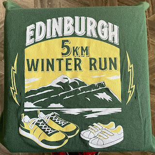 The Edinburgh Winter Run logo on a green shirt. The logo features shoes and an outline of Arthur's Seat,