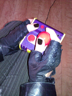 [image Description] Photo of a colorful joystick held by two hands in black fingerless gloves and black leather jacket.