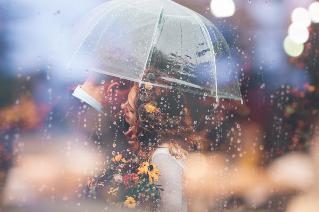 Couple happily enjoying rain under single umbrella