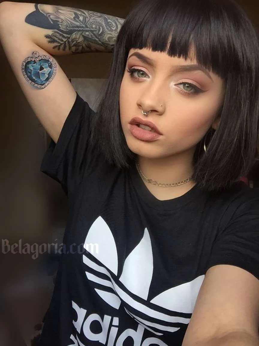 Foto de una mujer con tatuaje de corazon diamante en el brazo