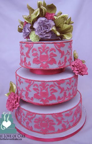 Three tier round wedding cake with pink damask pattern over light purple 