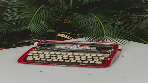 Vintage red working man typewriter on a white garden table.