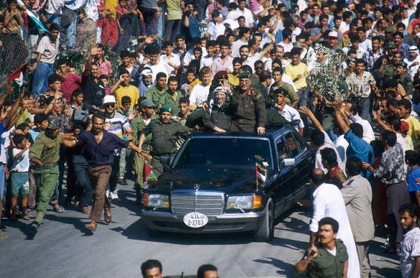 Yasser 'Arafat returns in triumph, surrounded by a crowd of Palestinians