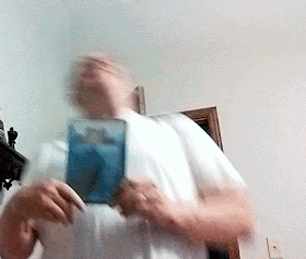 An animation of the author hopping from side to side with his head thrown back, laughing in delight, as he holds the DVD case for the film Dark Dungeons. He is an overweight white guy wearing glasses and a white t-shirt, with long brown hair pulled back in a ponytail.