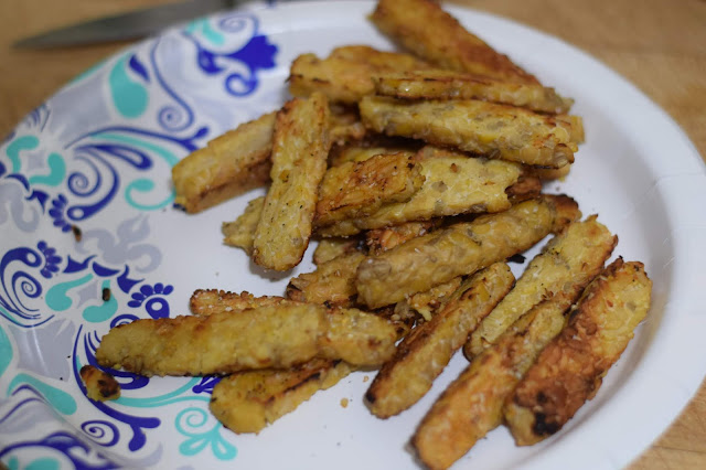 The cooked tempeh on a paper plate, on the counter. 