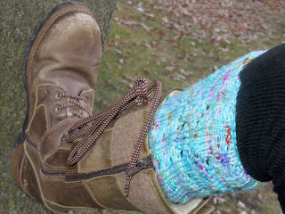 Someone wearing a sky blue boot topper knit in worsted yarn; with lace eyelets visible