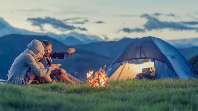 People by campfire and tent