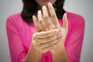 A woman holding her hand in pain | Chiropractor near me