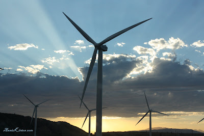 windmills and the sun set with beams of lights bursting through the clouds