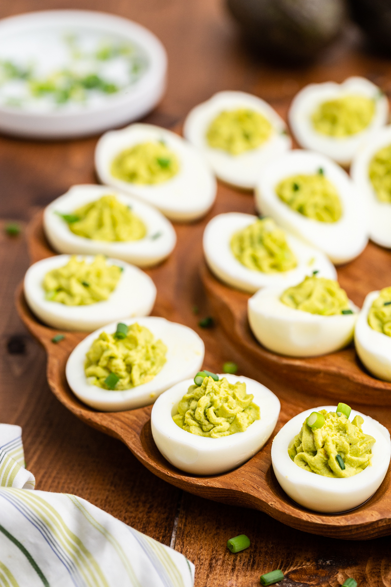 Avocado Deviled Eggs on a wooden Deviled Egg Tray.