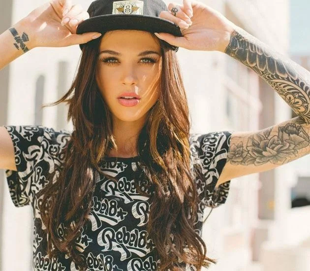 Modelo de mirada penetrante, posando se sujeta su gorra vemos tatuajes en sus brazos