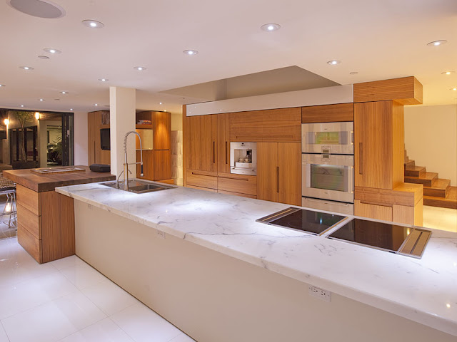 Photo of wooden furniture in the kitchen along with the huge kitchen island with marble surface 