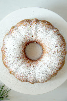 Bezuckerter Marmorgugelhupf von oben fotografiert auf einer weißen Kuchenplatte.