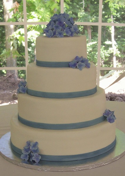 Four tier round wedding cake with pastel blue hydrangeas and pastel blue 
