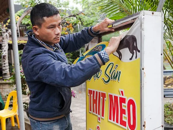 Pham Quoc Doanh, the restaurant owner tears down the signage on the closure of his cat meat restaurant.