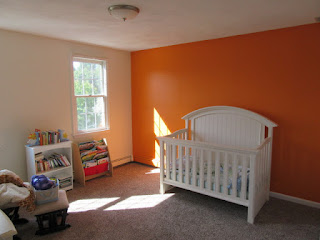 Baby's nursery with orange accent wall.