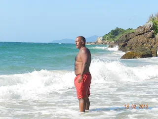 Jorge parado, solo, en la playa, con el agua hasta los tobillos.