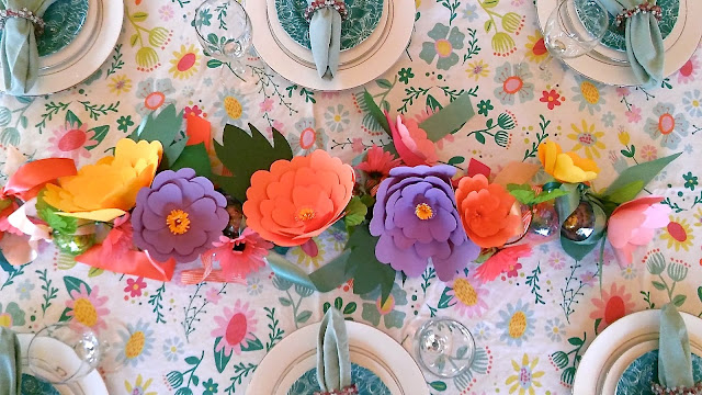 the finished Easter Egg & Paper Flower Easter Garland with flowers and easter eggs tied up with ribbons laying as a centerpiece in the middle of a set Easter table