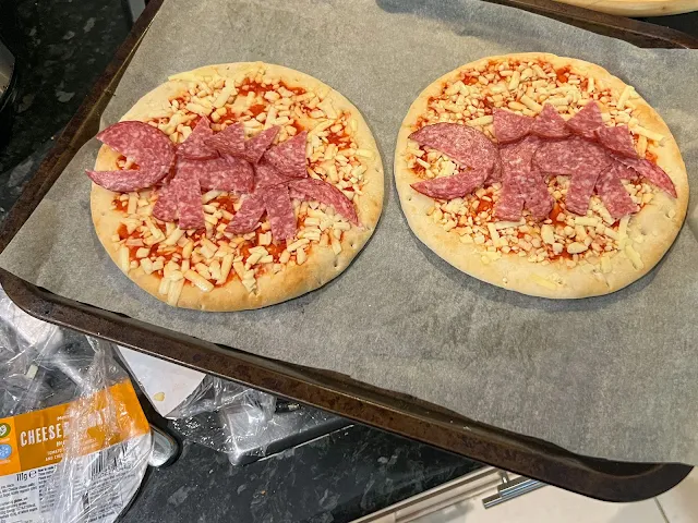 Small pizzas with a pepperoni dinosaur on each ready to cook