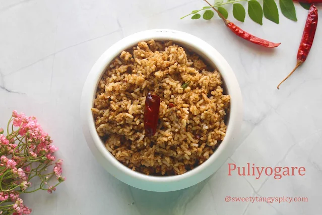 "A tempting plate of Puliyogare, a tangy and flavorful South Indian rice dish, garnished with curry leaves and served with a side of crunchy papadums."