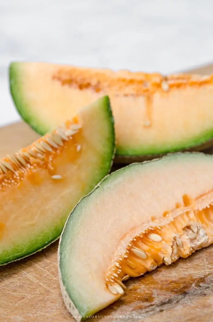 Slices of cantaloupe with seeds on cutting board