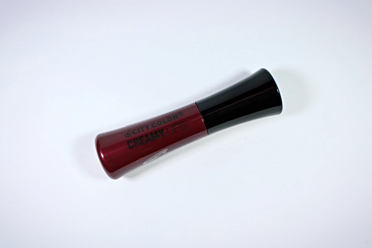 a close-up of City Color Creamy Lips in the shade 'Chocolate Merlot' on a blue background