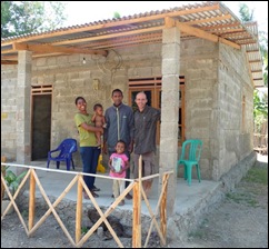 Sinta with her husband Apoli and 2 neices proudly standing outside their newly finished home.