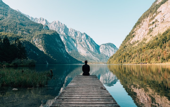 -person-sitting-on-wooden-planks-across-the-lake-scenery