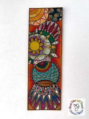 A circular patterned illustrated bookmark lies on a white table. It is brightly colored and fun to look at.