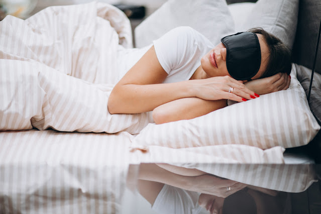 devojka spava na stranu (bok) pokrivena jorganom sa maskom za spavanje