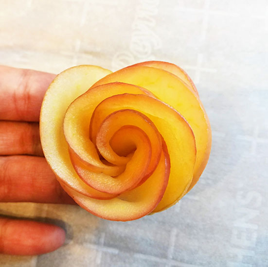 Holding a rose made with thinly sliced apples