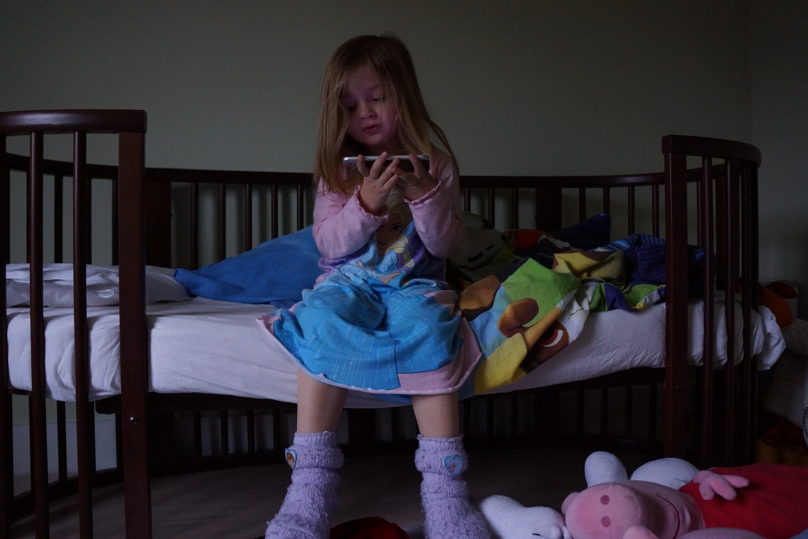 toddler girl sitting on bed watching a mobile film