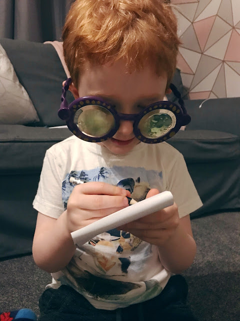 Little boy wearing the googly eye glasses and holding the pad and pen