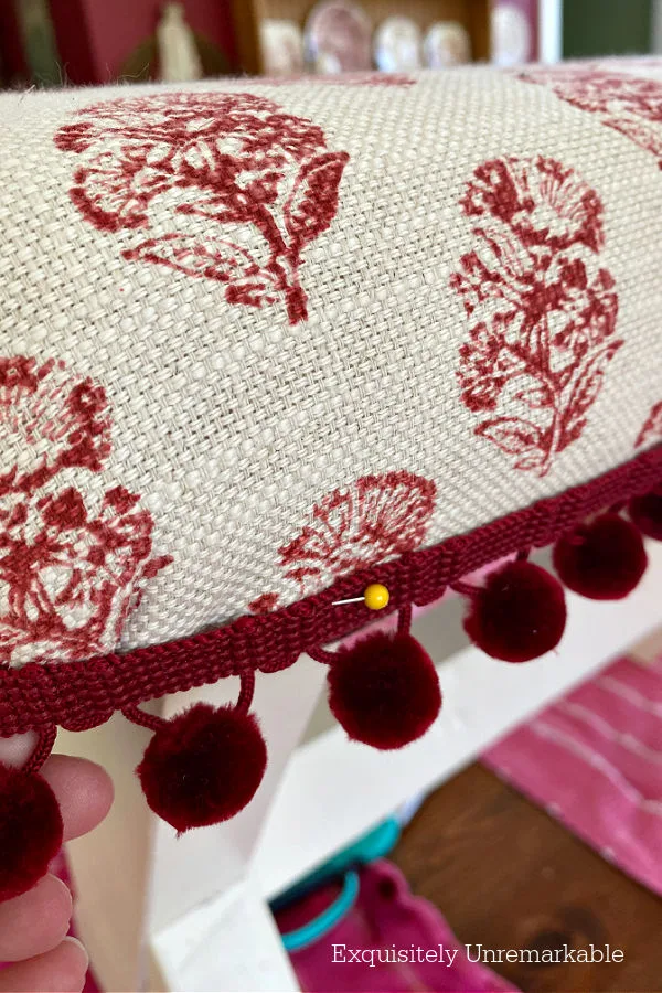 Pinning Red Pom Pom Trim To An Upholstered Bench