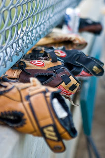 photo of softball gloves lined up in the dug out