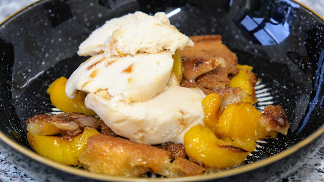 Peach Cobbler with ice-cream in a black bowl