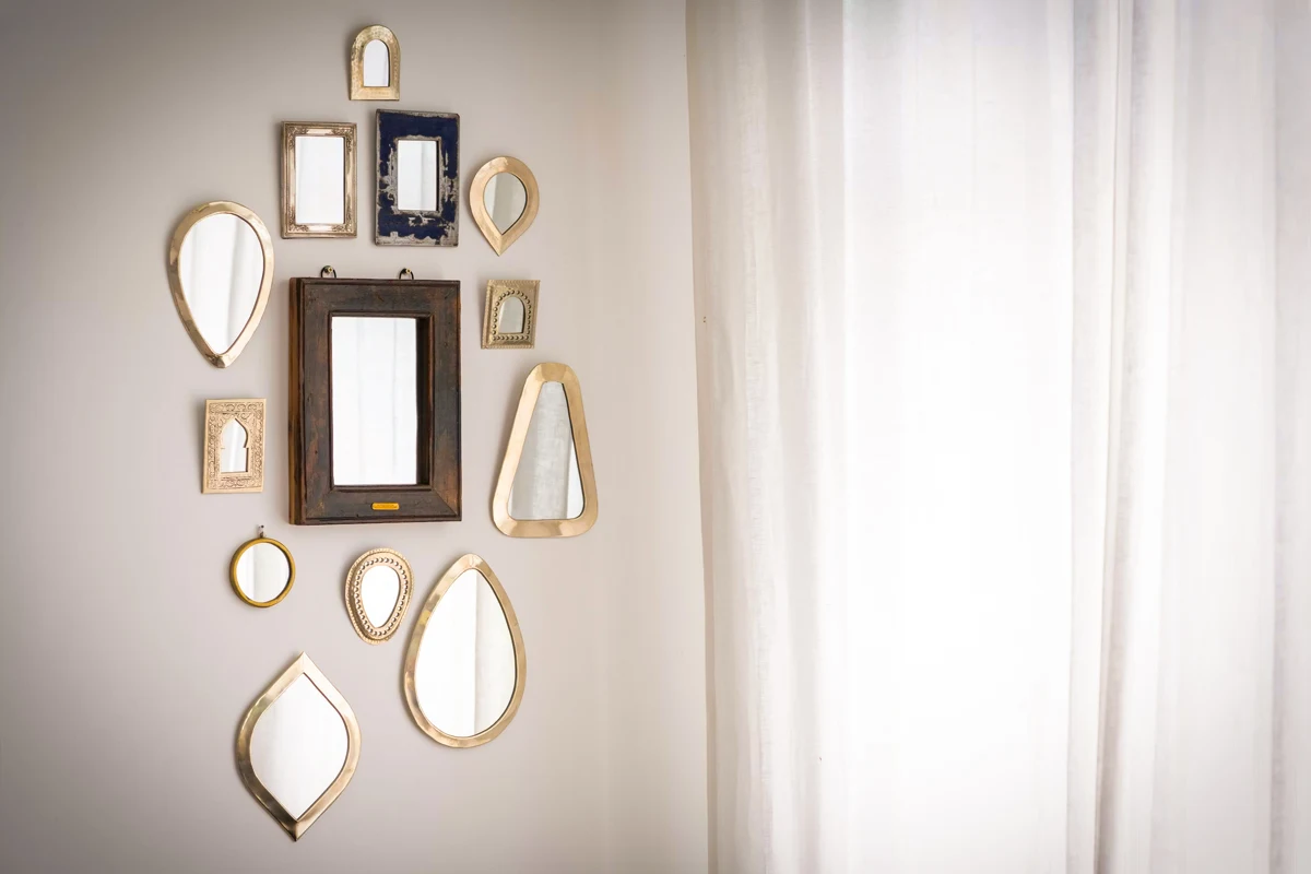 various small mirrors are hanging on a cream-colored wall