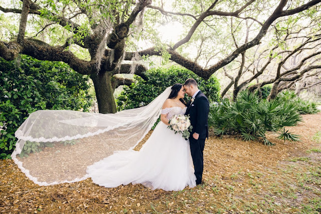 bride and groom smiling with veil blowing in the wind