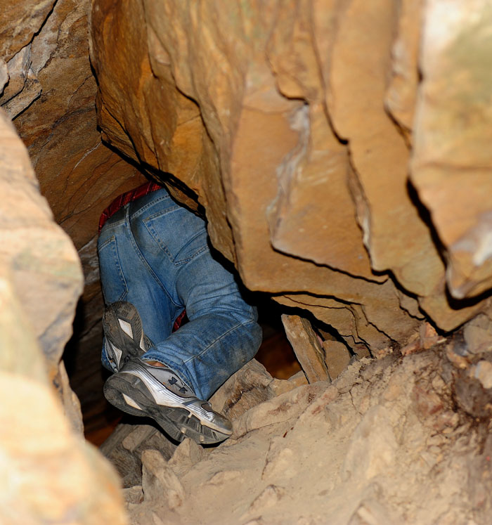 Matthew Riccetti climbing up through small caves at Cumber Falls State Park in Kentucky.