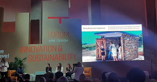 uma mulher a apresentar um slide sobre turismo sustentável no palco do Fórum de Enoturismo