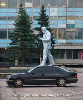 Big statue appears to be walking on top of a mercedes car.