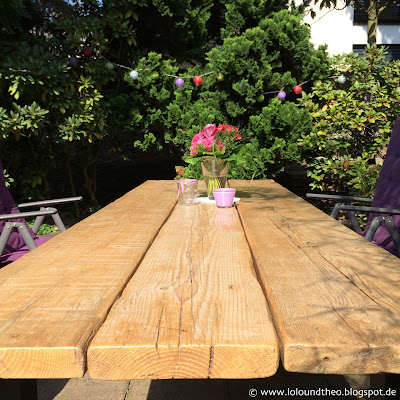 Gartentisch mit Blumenvase, Windlichtern und Häkeldeckchen